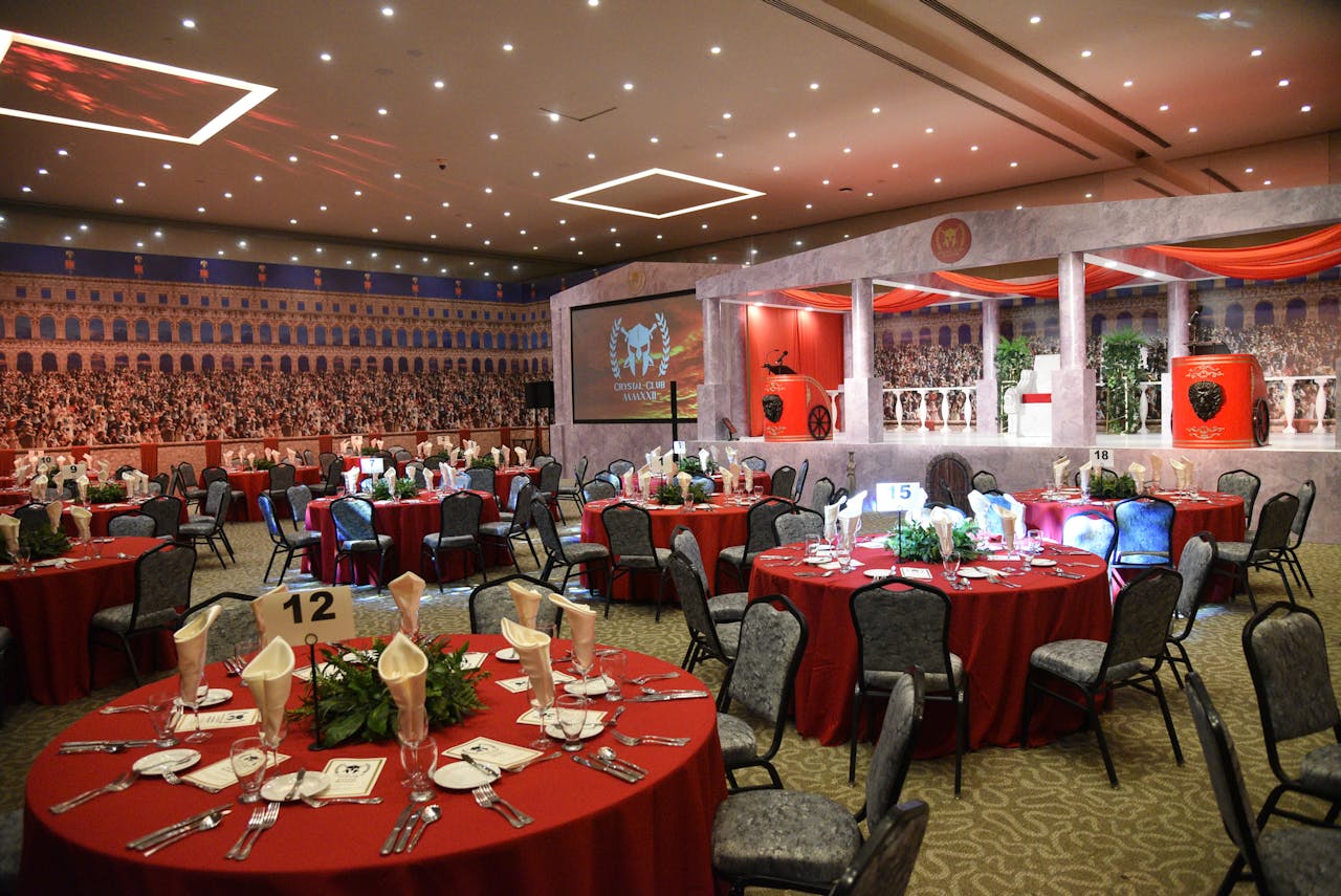 Luxurious setup for a Roman-themed event with red table settings, ideal for formal dinners or parties.